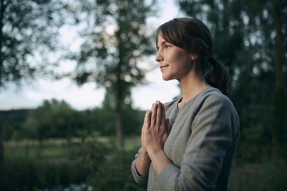Frau faltet die Hände vor der Brust und macht Yoga