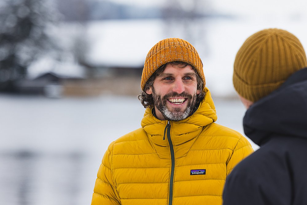 Lachender Ben Göller vor einem verschneiten See