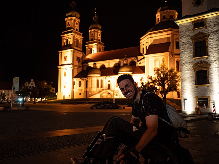 Moritz Brückner im Rollstuhl nachts vor der erleuchteten Basilika in Kempten