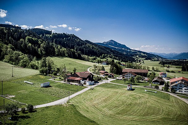 Das Hühnermobil in einer Drohenaufnahme mit den Allgäuer Bergen im Hintergrund