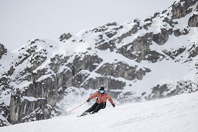 Eine Skifahrerin bei einer schnellen Abfahrt, im Hintergrund eine Felswand