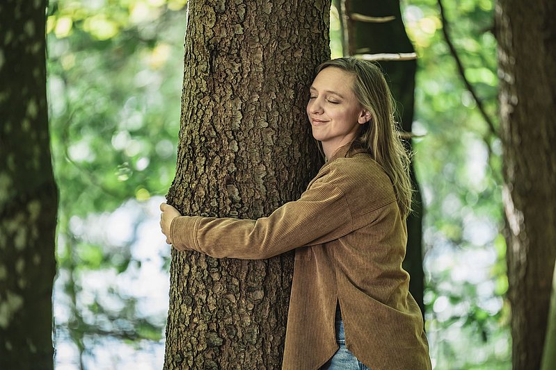 Frau umarmt einen Baum