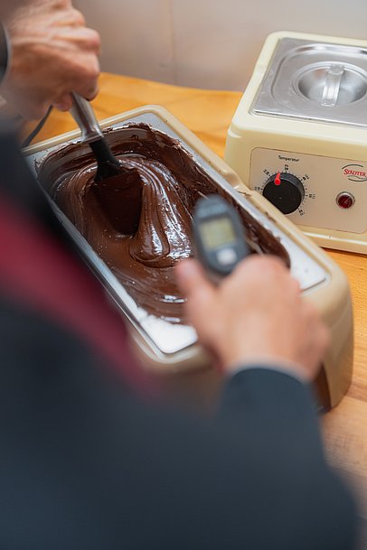 Chocolatier Jonathan Baldinger misst die Temperatur von flüssiger Schokolade