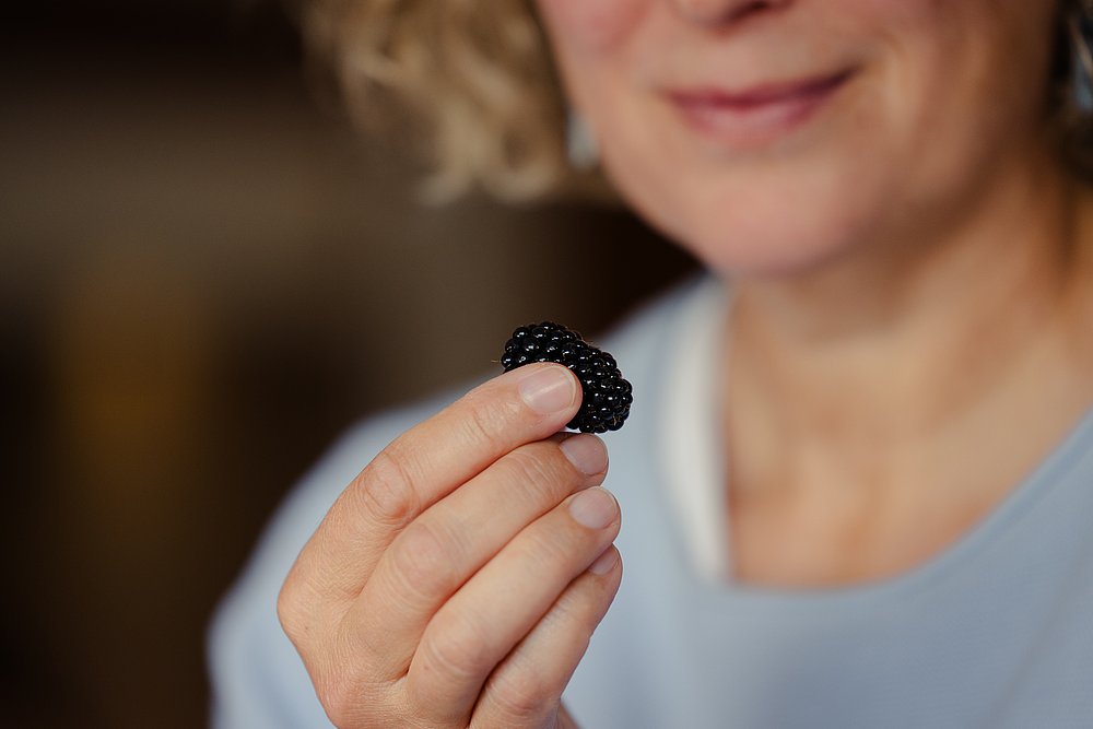 Frau mit Brombeere in der Hand