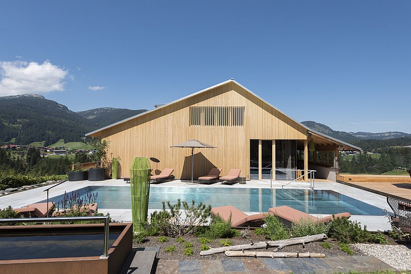 Holzfassade des Oswalda Hus mit Pool, Sonnenliegen und Kneippbecken