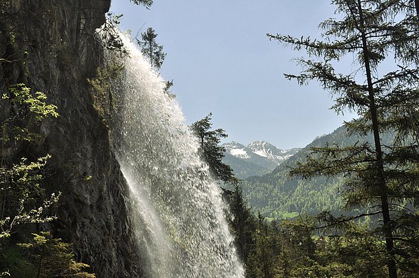 Wasserfall von der Seite, Felswand und Blick auf Berge im Hintergrund