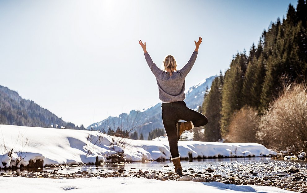 Frau macht Yogaübung in Winterlandschaft