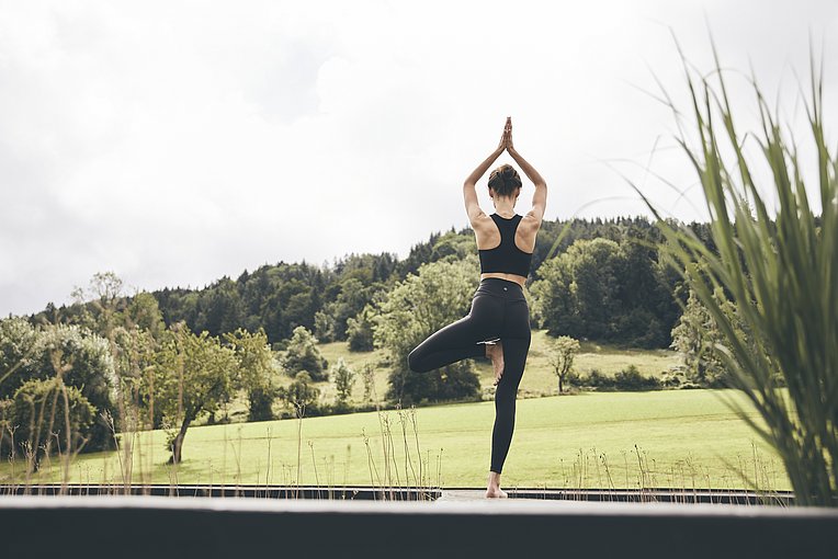 Frau von hinten im Grünen macht Yoga