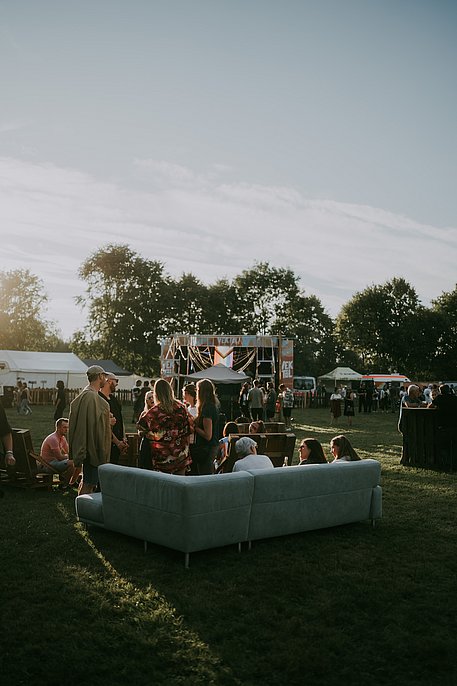 Festival-Besucher sitzen auf einem Sofa in der Wiese vor der Hauptbühne auf dem Vektol Festival Marktoberdorf