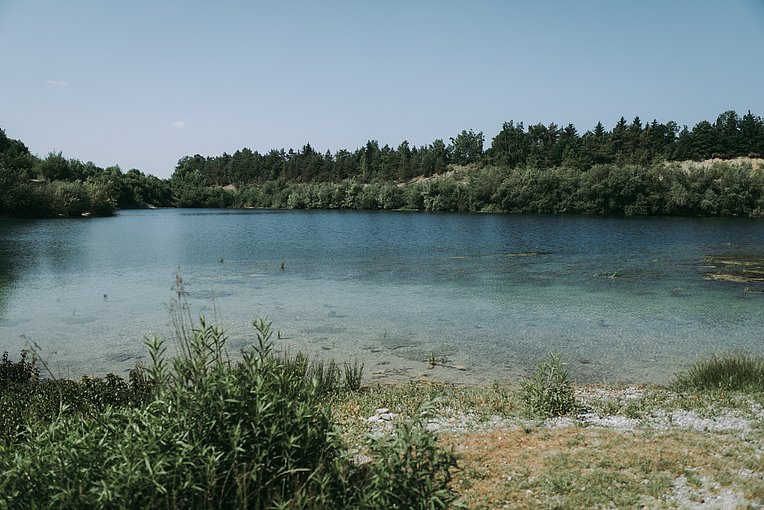 Aitrachsee mit klarem, türkisfarbenen Wasser und bewaldetem Ufer