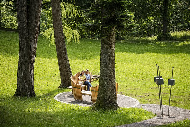 Ein Paar auf einer Bank zwischen großen Bäumen im Park