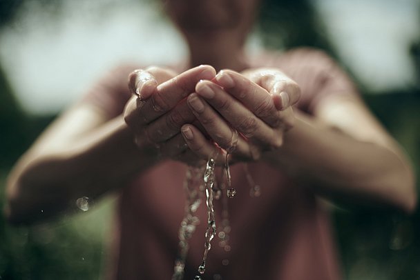 Wasser rinnt durch die Hände einer Frau