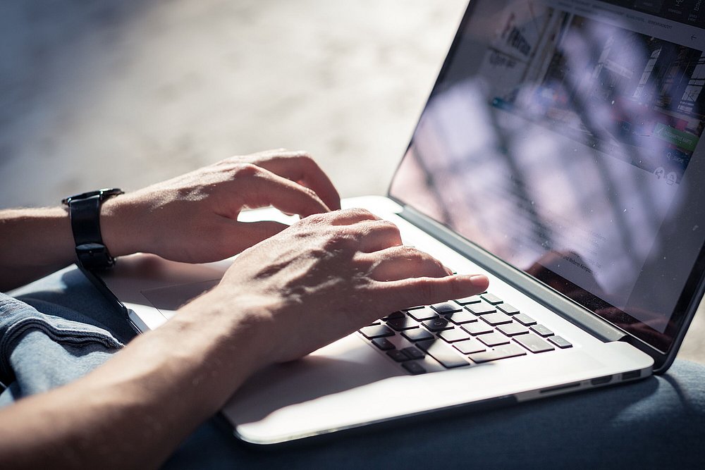 Arbeiten am Laptop - Finger tippen auf einer Tastatur