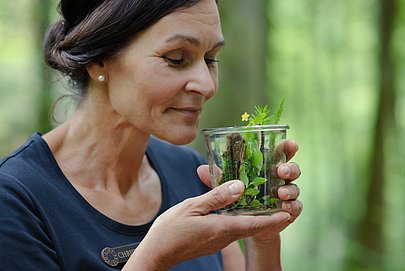 Christiane Haibel im Wald, riecht an einem Glas voll Fichtennadeln