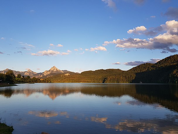 Weißensee mit bewaldeten Hügeln und Bergen, die sich im Wasser spiegeln