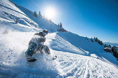 Rodler in einer rasanten Kurve, der Schnee staubt