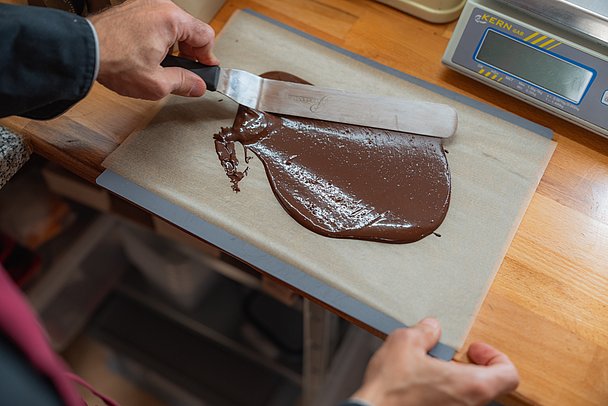 Chocolatier Jonathan Baldinger verstreicht flüssige Schokolade auf einem Papier