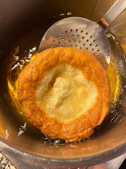 Ein fertiges Funkenküchle wird aus dem Topf geholt