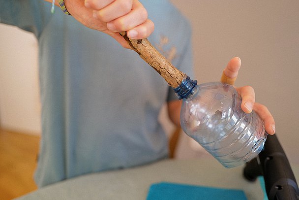 Fackel basteln: Ast wird in abgeschnittene Wasserflasche gesteckt