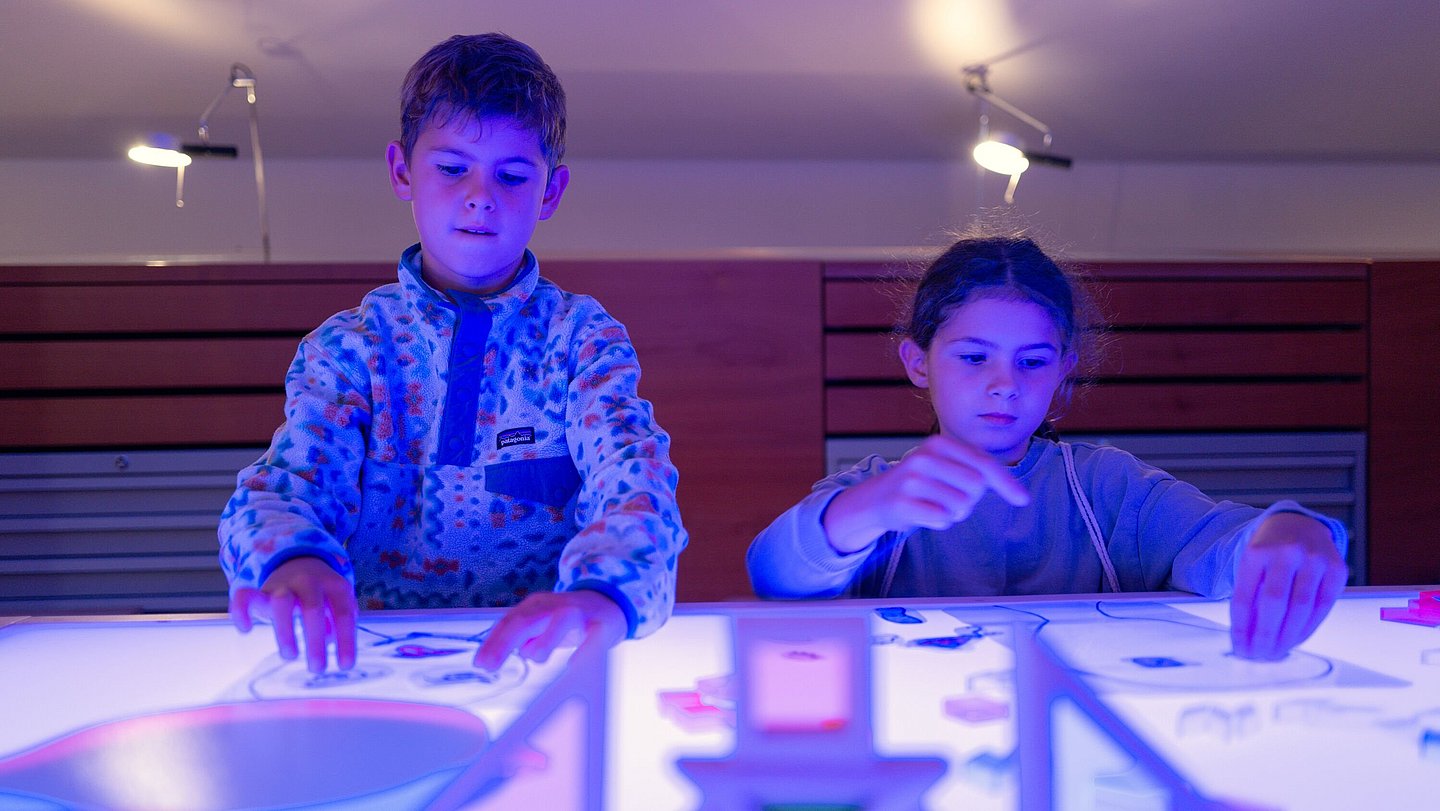 Kinder legen Bilder auf leuchtender Platte im Museum Kinder legen Bilder auf leuchtender Platte im Museum