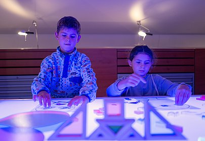 Kinder legen Bilder auf leuchtender Platte im Museum