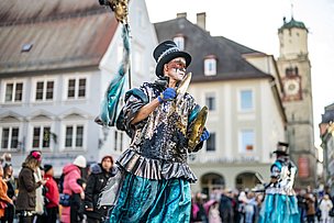 Verkleideter Guggenmusiker spielt Becken in der Memminger Altstadt