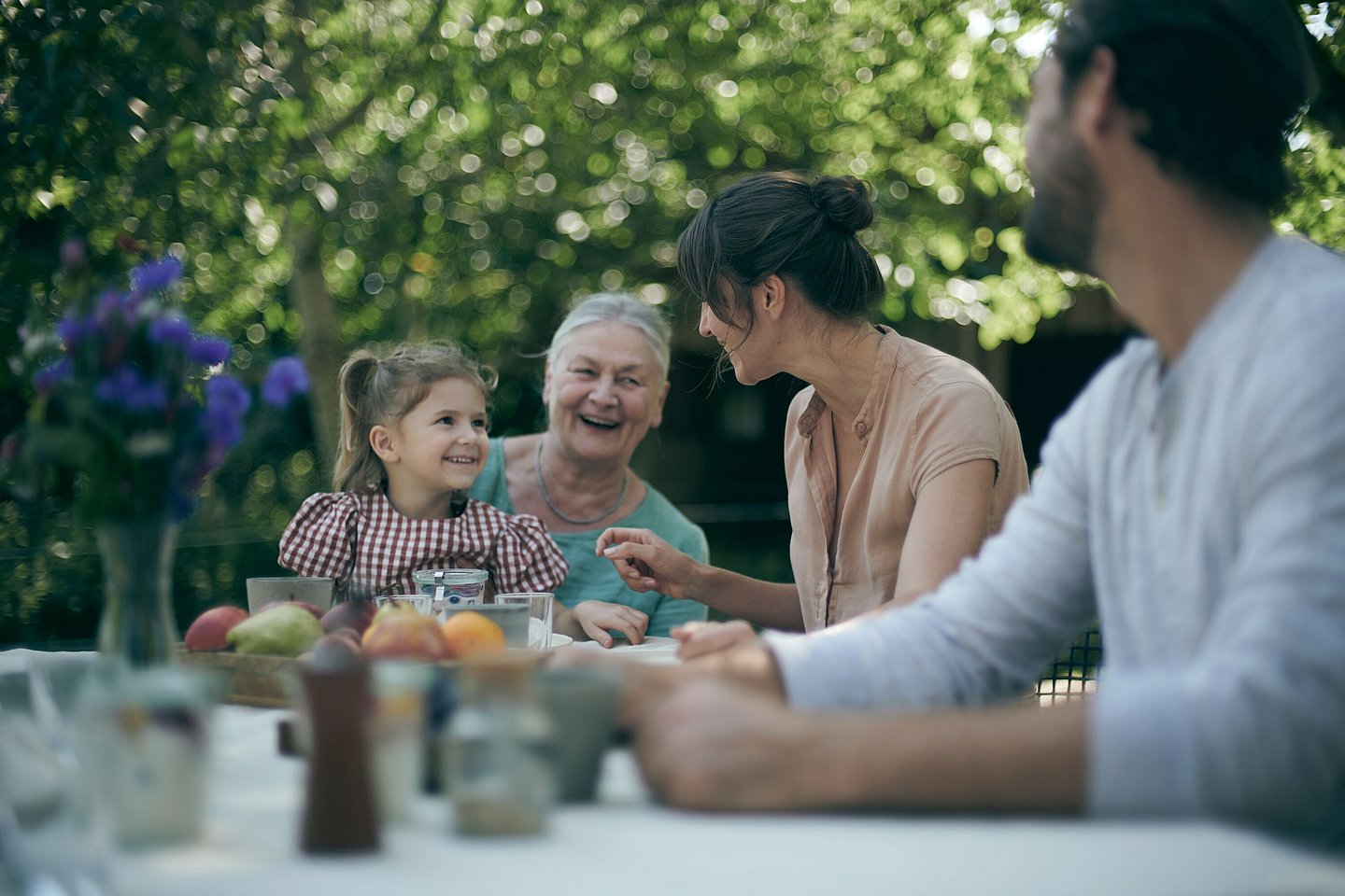 Lachende Familie an einem Tisch im Garten