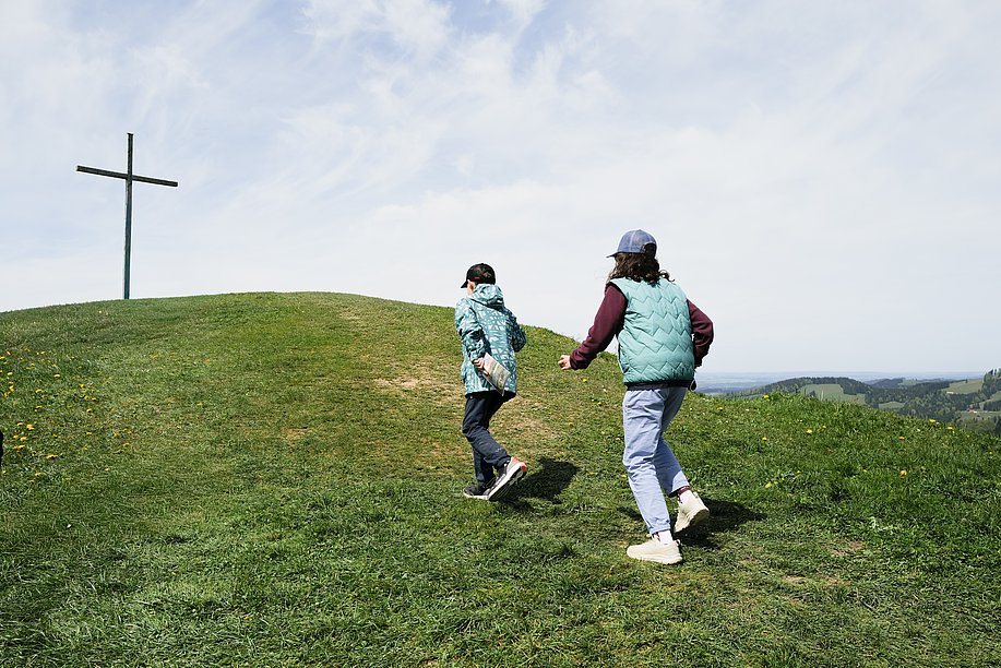 Junge und Mädchen auf dem Weg zu einem Gipfelkreuz