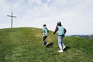 Junge und Mädchen auf dem Weg zu einem Gipfelkreuz