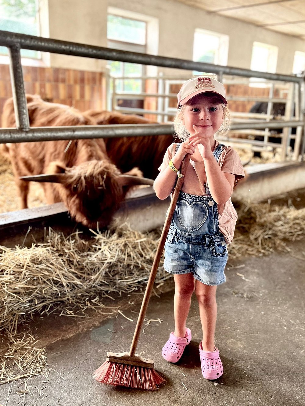 Mädchen mit einem Besen in einem Kuhstall Mädchen mit einem Besen in einem Kuhstall