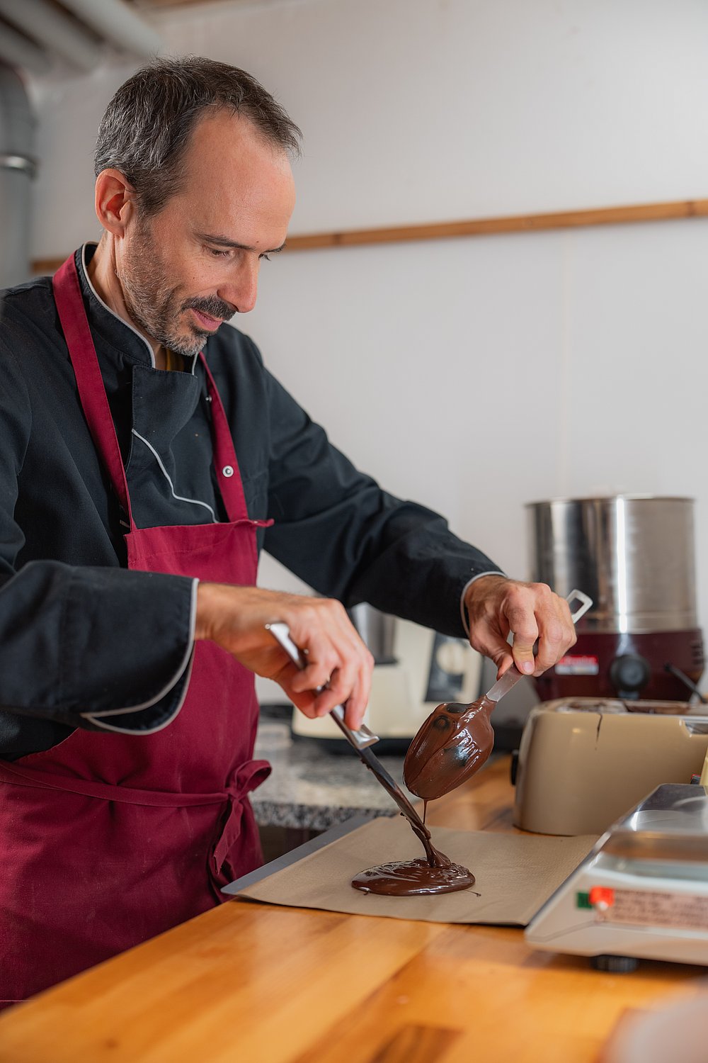 Chocolatier Jonathan Baldinger gibt flüssige Schokolade aus ein Papier