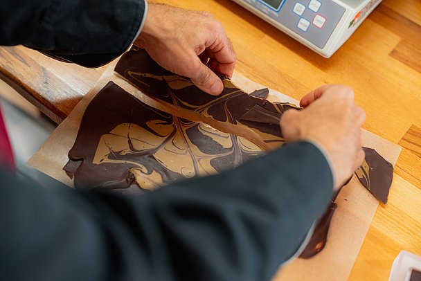 Chocolatier Jonathan Baldinger bricht Schokolade auseinander