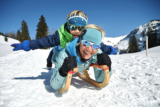 Mutter mit Sohn mit den Köpfen nach vorn auf einem Schlitten