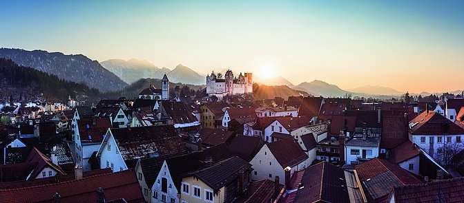 Die Sonne leuchtet hinter dem Hohen Schloss auf ein winterliches Füssen