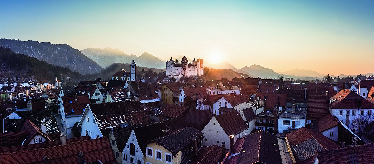 Die Sonne leuchtet hinter dem Hohen Schloss auf ein winterliches Füssen
