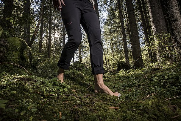 Frau geht barfuß über Waldboden