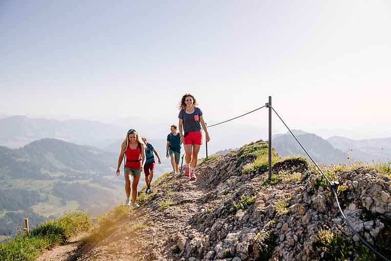 Wandergruppe auf einem Gratweg, im Hintergrund Berge