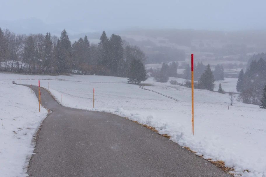 Ein geteerter Weg führt durch die verschneiten Felder talabwärts von Zell nach Eisenberg.