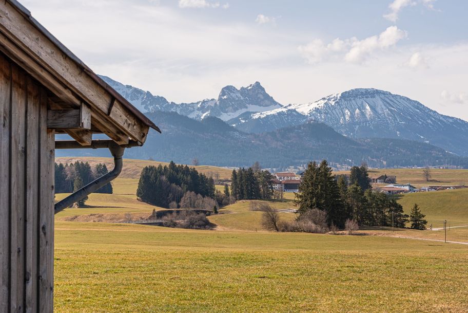 Blick über Felder in die verschneiten Berge mit Aggenstein und Breitenberg.