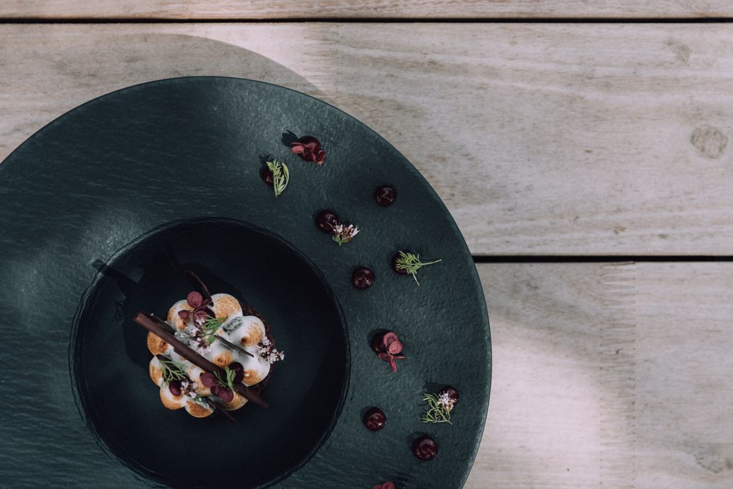 naturhotel_chesa_valisa_kulinarik_speisen_essen_holztisch_teller_schwarz_sommerlich_2