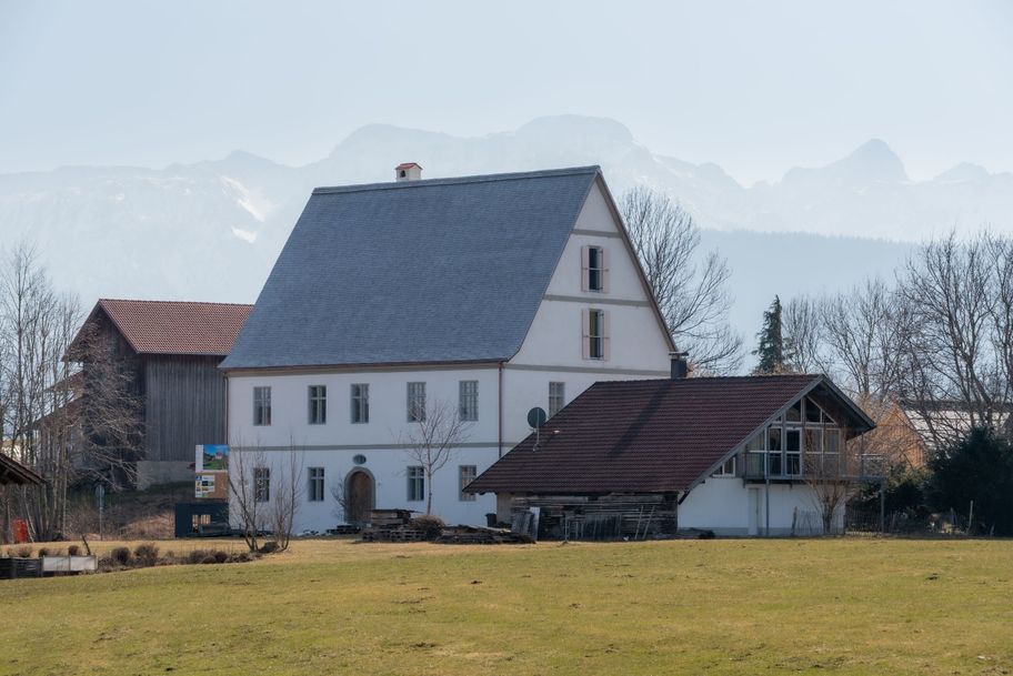 Ehemaliges Schloss Weizern vor Bergkulisse.