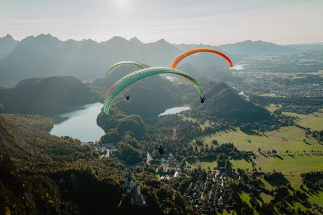Drei Paragleiter über Schwangau mit Schloss Neuschwanstein und dem Alpsee