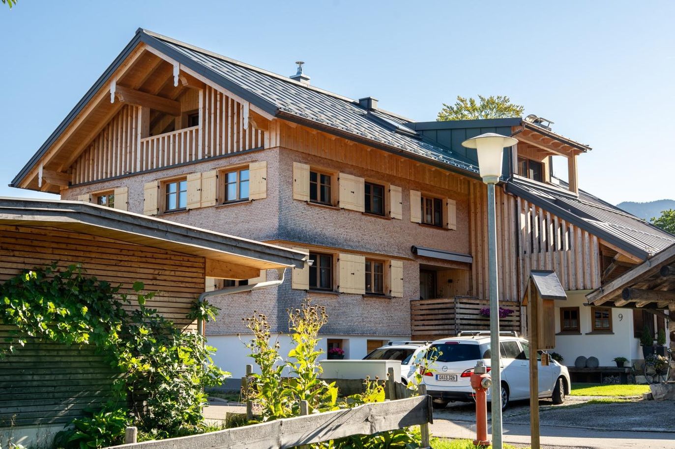 Hausansicht mit Holzfassade und Parkplatz