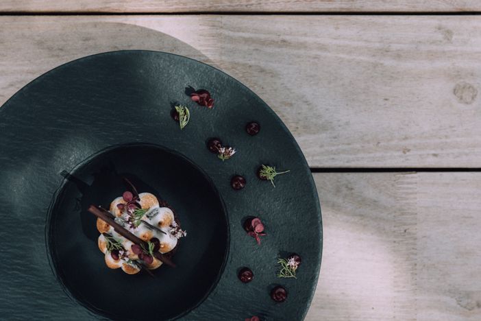 naturhotel_chesa_valisa_kulinarik_speisen_essen_holztisch_teller_schwarz_sommerlich_2