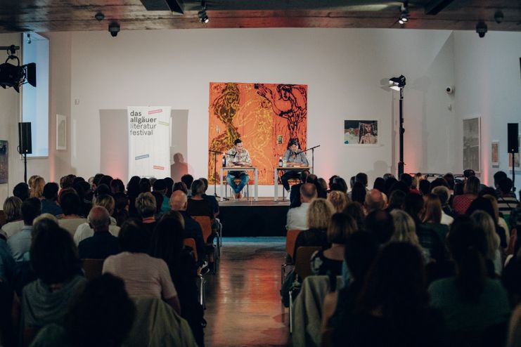 2 Herren sitzen auf der Bühne vor einem sitzenden Publikum literaturfestival ottobeuren Kunst und Kulturraum 2022 ©Allgäu GmbH, by Philip Herzhoff - Isenhoff