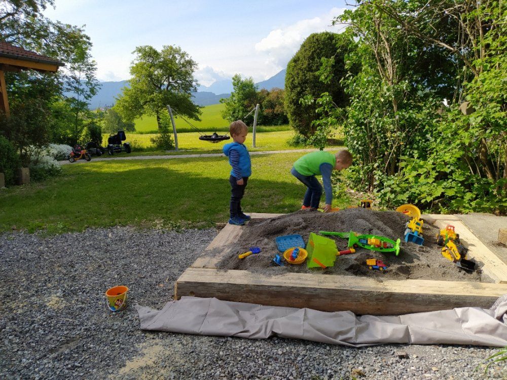 Sandkasten und Nestschaukel am Haus