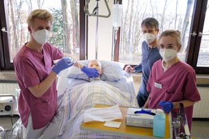 Lehrer Sedlacek mit zwei Auszubildenden bei einer Praxisübung an einer Patientenpuppe.